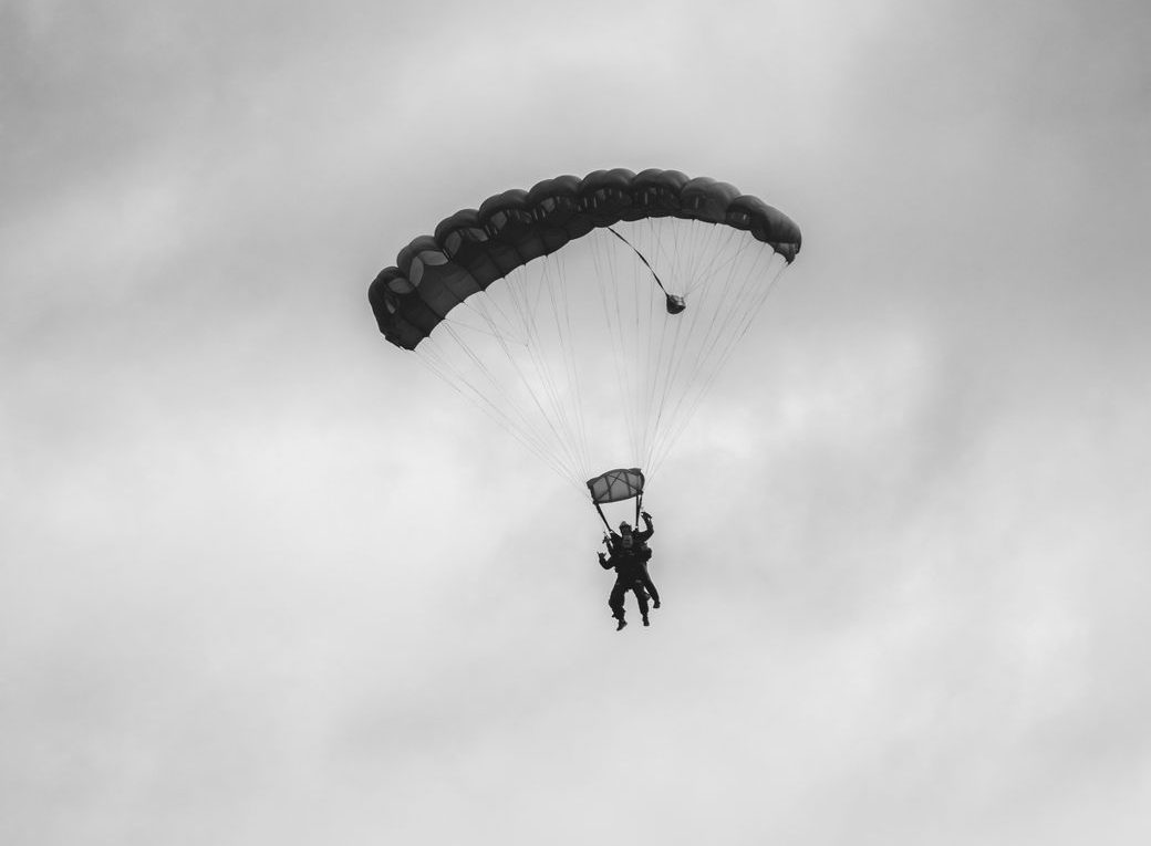 a black and white photo of a person flying with a parachute