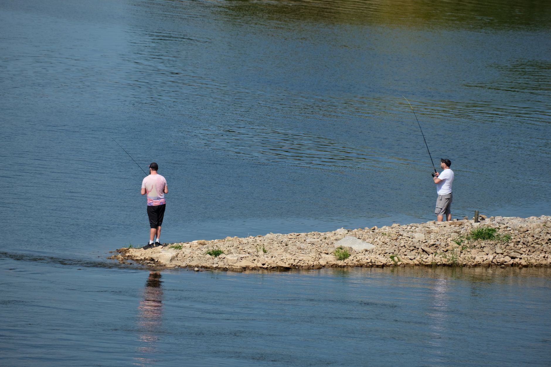 two men fishing by a calm lakeside